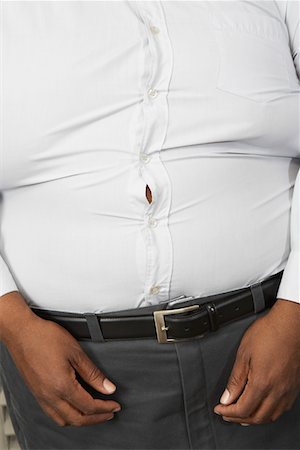 fat black man standing - Overweight man wearing tight shirt, mid section Stock Photo - Premium Royalty-Free, Code: 694-03327437