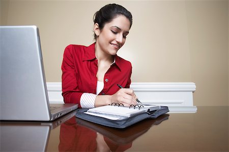 Business woman writing in diary beside laptop in office Stock Photo - Premium Royalty-Free, Code: 694-03327617