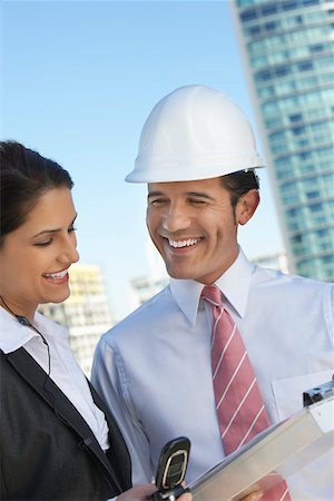 person on phone with clipboard - Businessman in hardhat showing clipboard to businesswoman Stock Photo - Premium Royalty-Free, Code: 694-03327809