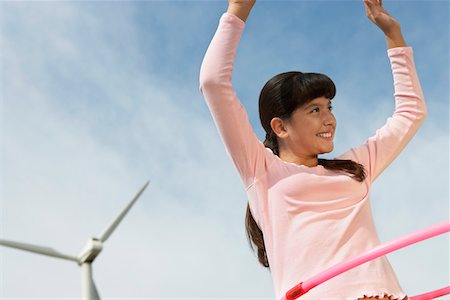 Girl (7-9) playing with hula hoop at wind farm Stock Photo - Premium Royalty-Free, Code: 694-03328185