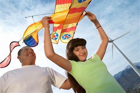 Girl (7-9) holding airplane kite with father at wind farm Stock Photo - Premium Royalty-Free, Code: 694-03328182