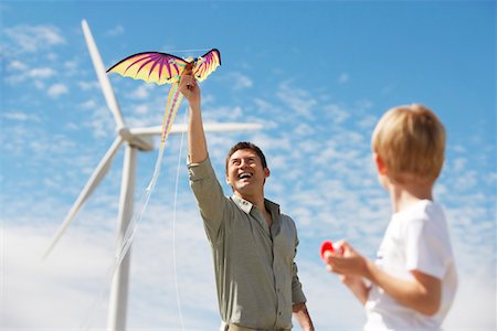 dragon toy - Father and son (7-9) playing with kite at wind farm Stock Photo - Premium Royalty-Free, Code: 694-03328221
