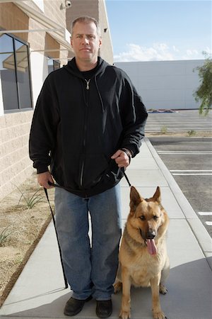 security guard - Portrait of security guard with dog, outdoors Stock Photo - Premium Royalty-Free, Code: 694-03328327