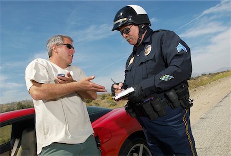 Traffic cop talking with driver of sports car Stock Photo - Premium Royalty-Free, Code: 694-03328503