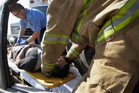 Firefighter and paramedics taking victim out of crashed car Fotografie stock - Premium Royalty-Free, Codice: 694-03328552