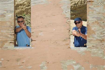 simsearch:694-03328608,k - Two men aiming hand guns at firing range Foto de stock - Royalty Free Premium, Número: 694-03328584