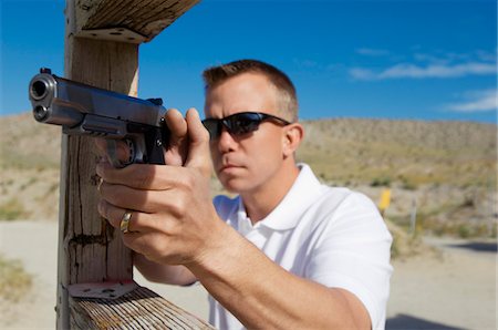 simsearch:694-03328608,k - Man aiming hand gun at firing range Foto de stock - Royalty Free Premium, Número: 694-03328599