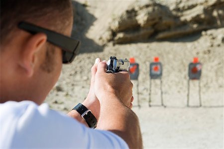 Man aiming hand gun at firing range Fotografie stock - Premium Royalty-Free, Codice: 694-03328614