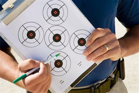 Instructor holding clipboard with target diagram, mid section Stock Photo - Premium Royalty-Free, Code: 694-03328642