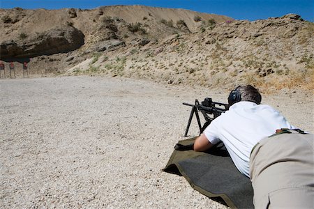 simsearch:694-03328595,k - Man aiming machine gun at firing range Fotografie stock - Premium Royalty-Free, Codice: 694-03328680