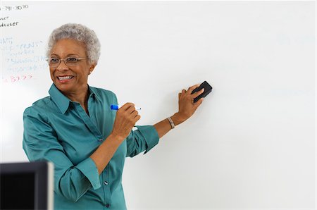 Female teacher erasing text on whiteboard in classroom Stock Photo - Premium Royalty-Free, Code: 694-03328784