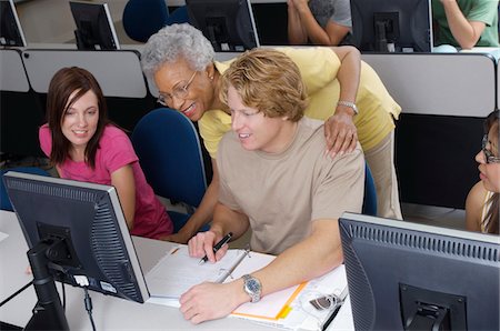 Enseignant aidant deux étudiants travaillant en salle informatique Photographie de stock - Premium Libres de Droits, Code: 694-03328814