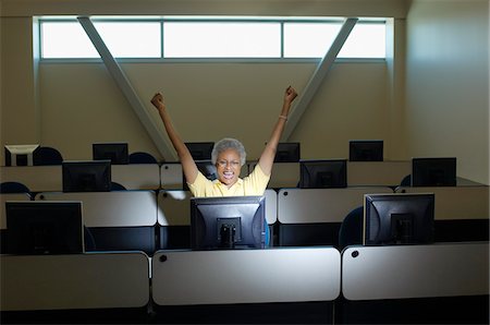 Mature female student celebrating in computer classroom Stock Photo - Premium Royalty-Free, Code: 694-03328823