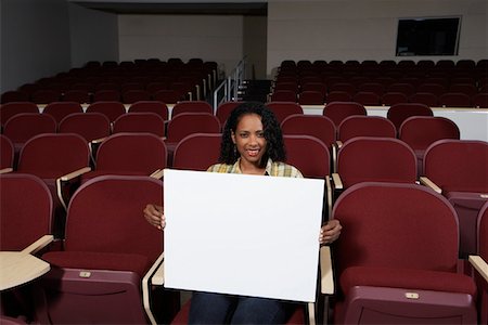 student in lecture hall - Female student holding blank board in lecture theatre, portrait Stock Photo - Premium Royalty-Free, Code: 694-03328894