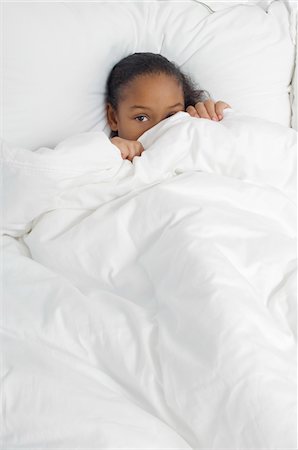 shy hiding - Girl (7-9) hiding under bed covers, portrait Stock Photo - Premium Royalty-Free, Code: 694-03329041