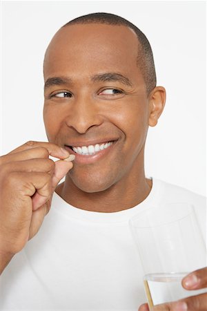 Man taking pills, holding glass of water, portrait Stock Photo - Premium Royalty-Free, Code: 694-03329106