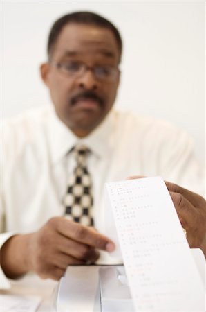 Businessman Reading an Adding Machine Tape Stock Photo - Premium Royalty-Free, Code: 694-03329401