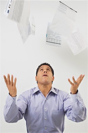 dettes - Homme jetant des formulaires fiscaux dans l'Air Photographie de stock - Premium Libres de Droits, Code: 694-03329469