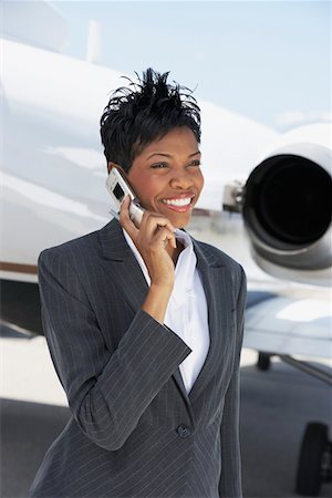 simsearch:693-03303406,k - Smiling Businesswoman standing outside Airplane, talking on mobile Foto de stock - Sin royalties Premium, Código: 694-03321999