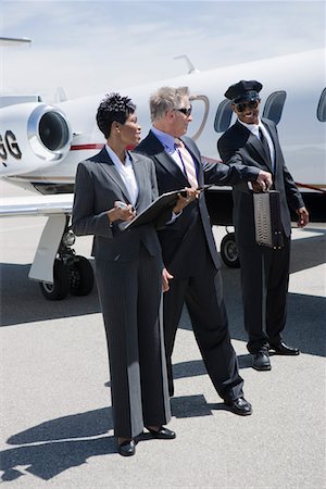 Senior businessman, mid-adult businesswoman and airline pilot in front of private jet. Stock Photo - Premium Royalty-Free, Code: 694-03322046