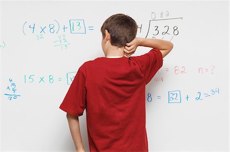 Schoolboy standing against whiteboard, back view Stock Photo - Premium Royalty-Free, Code: 694-03330043