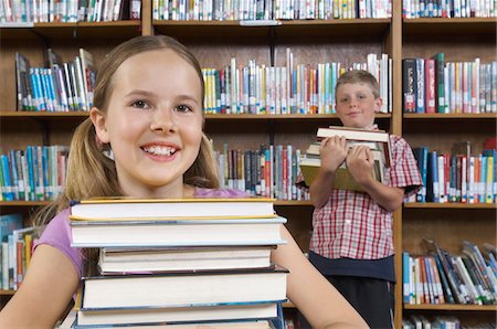 school girl holding pile of books - Two school children with books in library, portrait Stock Photo - Premium Royalty-Free, Code: 694-03330089