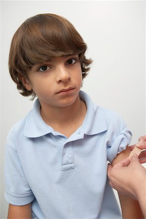 Nurse placing bandage on boy's arm Stock Photo - Premium Royalty-Free, Code: 694-03331652