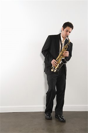 playing musical instrument - Mid adult man stands in suit playing the saxophone Stock Photo - Premium Royalty-Free, Code: 694-03332513