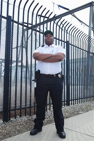 prison photograph - Security guard stands at strengthened prison fence Foto de stock - Sin royalties Premium, Código: 694-03474742