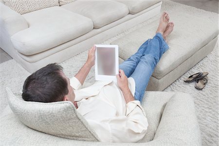 simsearch:694-03557934,k - Man sits with feet up reading a digital book Stock Photo - Premium Royalty-Free, Code: 694-03557939