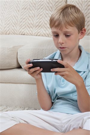 simsearch:694-03557934,k - Boys sits cross-legged with portable games console Stock Photo - Premium Royalty-Free, Code: 694-03557945