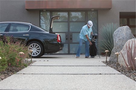 Man lifting golf bag into boot of luxury vehicle Stock Photo - Premium Royalty-Free, Code: 694-03557959
