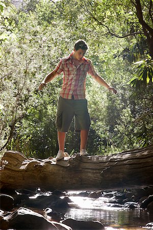 simsearch:694-03783289,k - Teenage boy (16-17 years) walking tree trunk above stream Stock Photo - Premium Royalty-Free, Code: 694-03694036