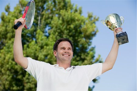 Man Holding up Tennis Rackets and Trophy on tennis court, low angle view Foto de stock - Sin royalties Premium, Código: 694-03692419