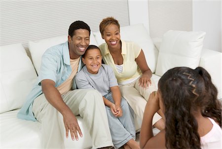 Girl Taking Picture of Family on sofa in living room Stock Photo - Premium Royalty-Free, Code: 694-03692439