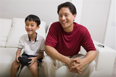 sofa two boys video game - Father watching son play video game on couch, front view Stock Photo - Premium Royalty-Free, Code: 694-03692467