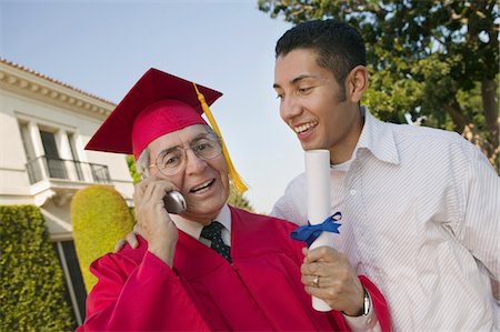 Senior Graduate using cell phone outside with son, low angle view Stock Photo - Premium Royalty-Free, Code: 694-03692636