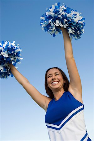 female teen in track and field - Smiling Cheerleader rising pom-poms, (low angle view) Stock Photo - Premium Royalty-Free, Code: 694-03692658