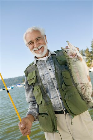 Middle-aged man holding up trout, smiling, (portrait) Stock Photo - Premium Royalty-Free, Code: 694-03692728