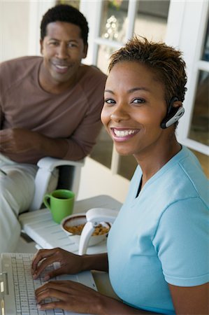 Femme utilisant un ordinateur portable sur le porche, le mari en arrière-plan, (portrait) Photographie de stock - Premium Libres de Droits, Code: 694-03692746