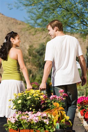 Young couple pulling cart with potted flowers in garden centre, rear view Stock Photo - Premium Royalty-Free, Code: 694-03693015