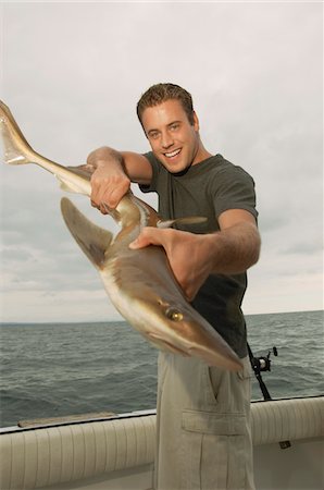 Sport fisherman displaying shark, (portrait) Stock Photo - Premium Royalty-Free, Code: 694-03693314