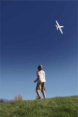 Boy stands on hilltop flying model plane Stock Photo - Premium Royalty-Free, Code: 694-03783191