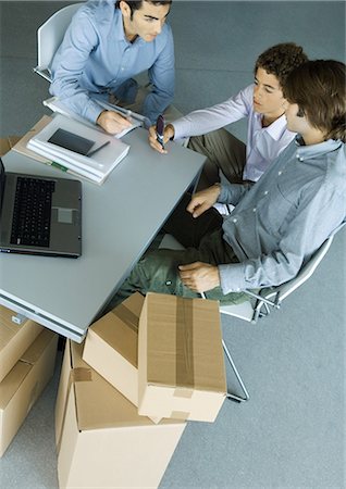 Three male colleagues grouped around desk, surrounded by cardboard boxes Foto de stock - Sin royalties Premium, Código: 695-05764148