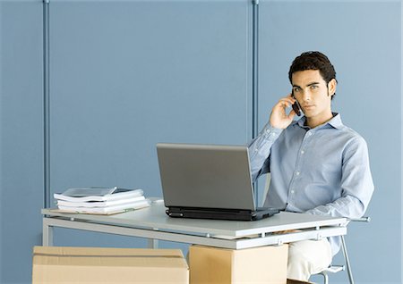 Man sitting at desk, using phone Stock Photo - Premium Royalty-Free, Code: 695-05764140