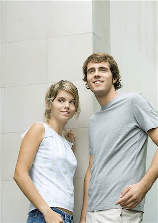 Young man and woman leaning against wall, smiling Stock Photo - Premium Royalty-Free, Code: 695-05764183