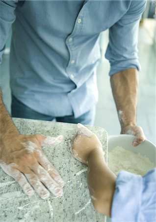 Girl and father wiping flour on counter into mixing bowl, cropped view Stock Photo - Premium Royalty-Free, Code: 695-05764218