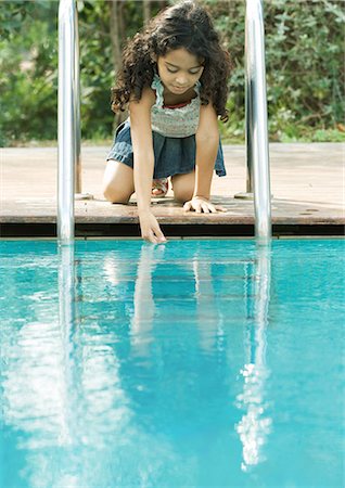 Girl crouching by edge of pool, touching surface of water Stock Photo - Premium Royalty-Free, Code: 695-05764238