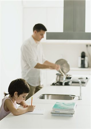 simsearch:695-03378625,k - Child doing homework on kitchen counter while father cooks Foto de stock - Royalty Free Premium, Número: 695-05764302
