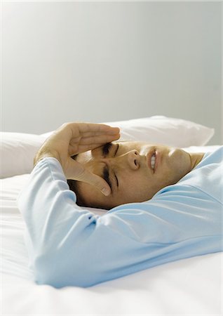 simsearch:695-05764382,k - Man lying on bed with hand on forehead, making face Stock Photo - Premium Royalty-Free, Code: 695-05764340